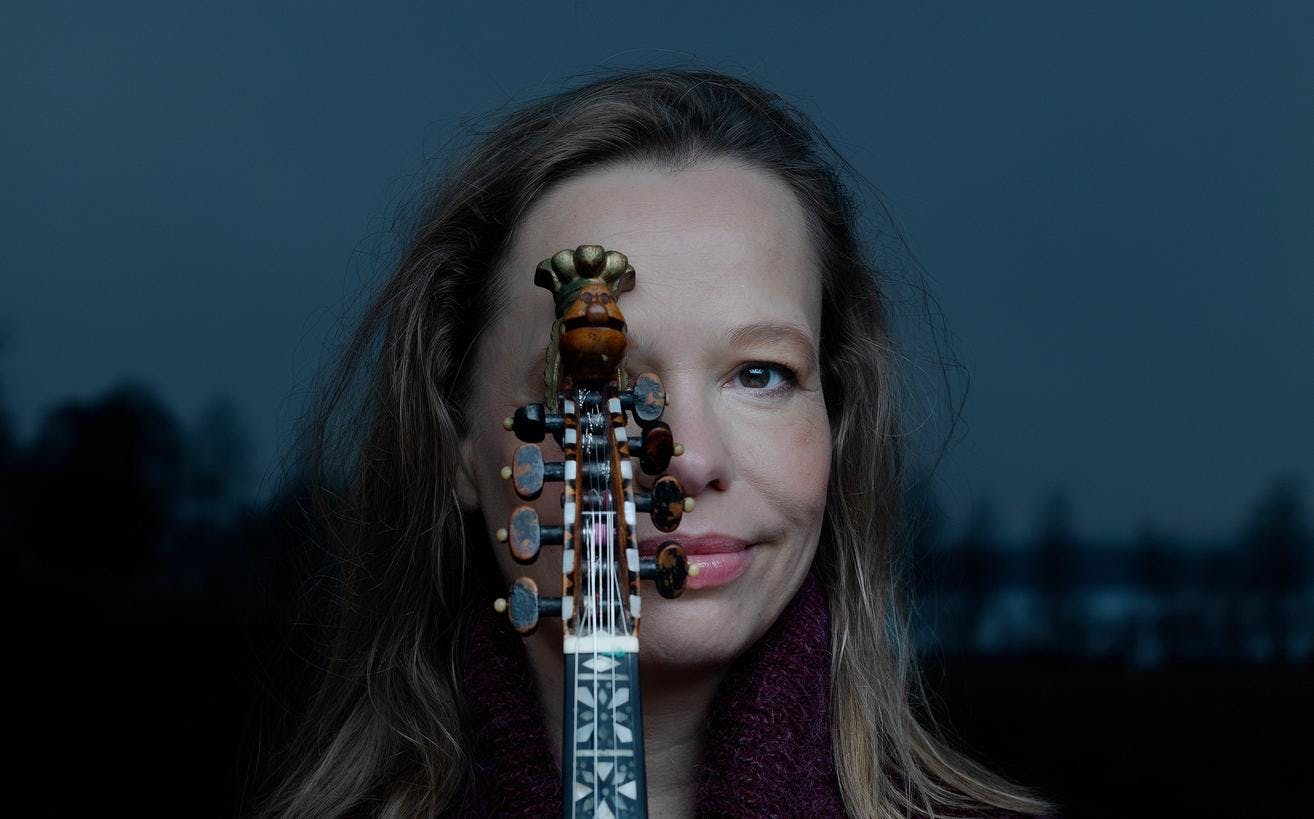 Et fotografi av folkemusiker Anne Hytta som holder hardingfelen sin opp foran halve ansiktet. 