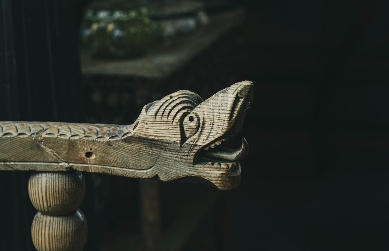 Detalj fra en stol i tre, som viser framstillingen av et dragehode