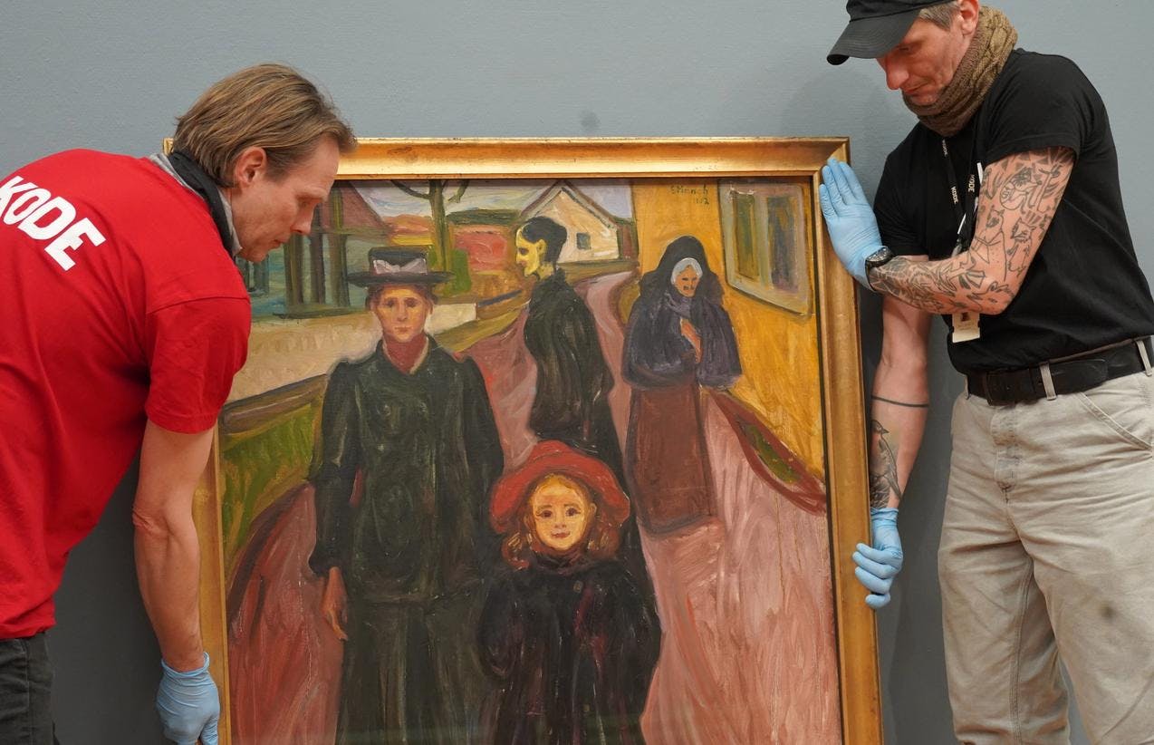 To menn i ferd med å løfte et maleri av Edvard Munch