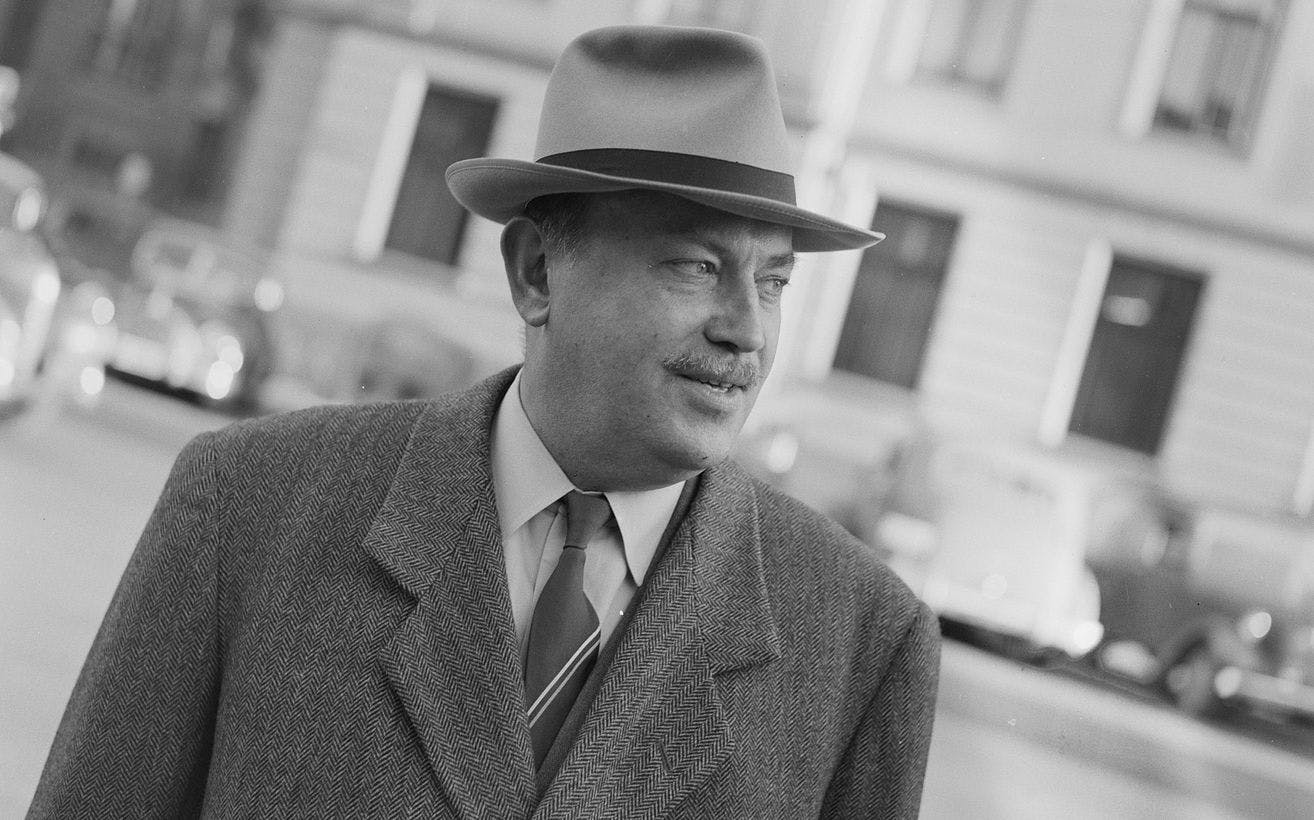 Sort-hvitt foto av en mann med hatt og frakk, som ser mot høyre.