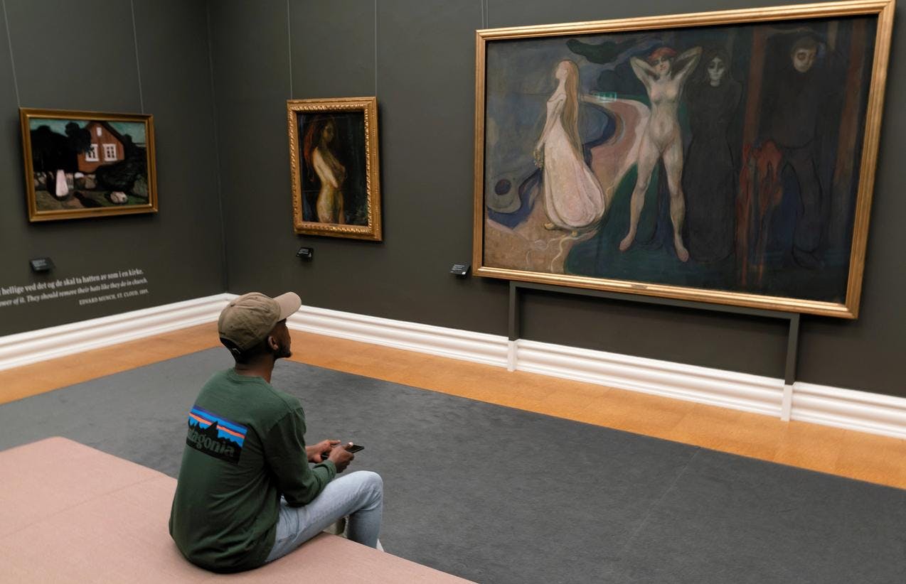 En person sitter foran et maleri av Edvard Munch