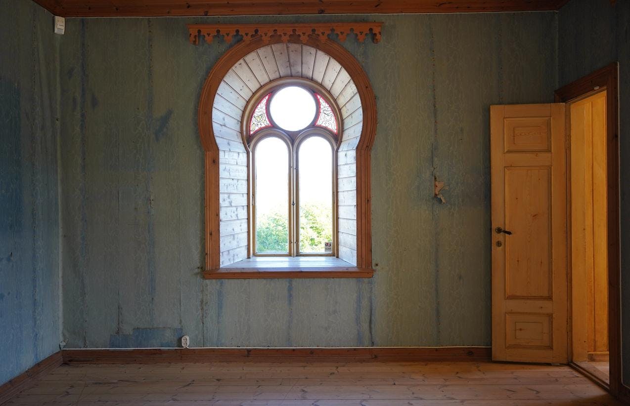 Fra underetasjen på Lysøen, i et tomt rom, hvor vi ser et vindu midt på veggen, mot en blå vegg