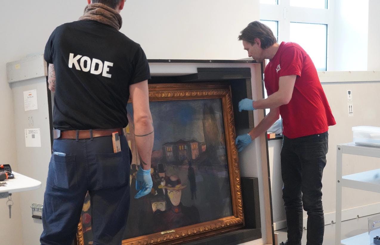 To menn pakker ut et maleri av Edvard Munch fra en stor kasse